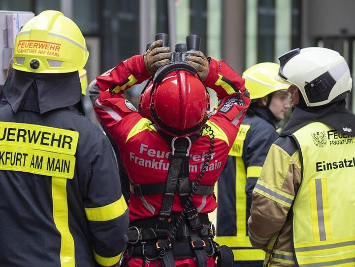 Mit dem Fernglas verfolgen Höhenretter der Frankfurter Feuerwehr vom Boden aus den Abstieg des Extremkletterers.