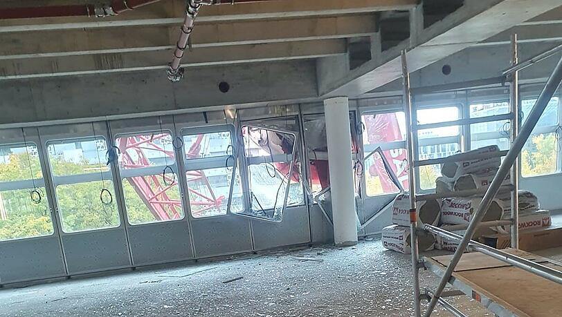 Zwei eingedrückte Fenster und jede Menge Glasscherben im Inneren des Gebäudes. Vor der Fensterfront ist der umgestürzte Kran zu erkennen.