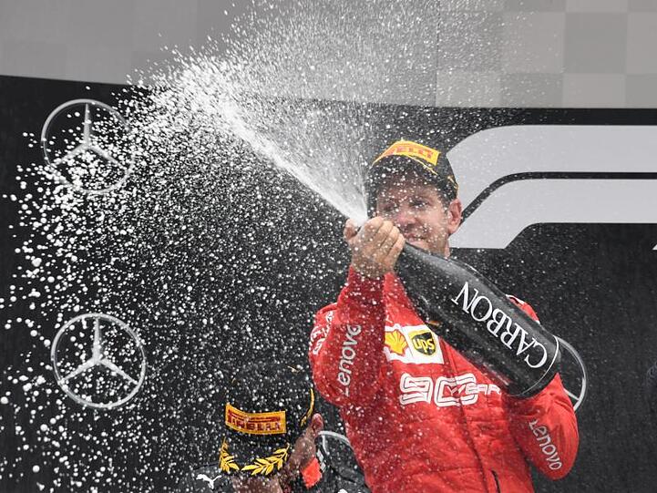 Nach der furiosen Aufholjagd spritzt der sichtlich zufriedene Ferrari-Pilot Champagner in die Menge.