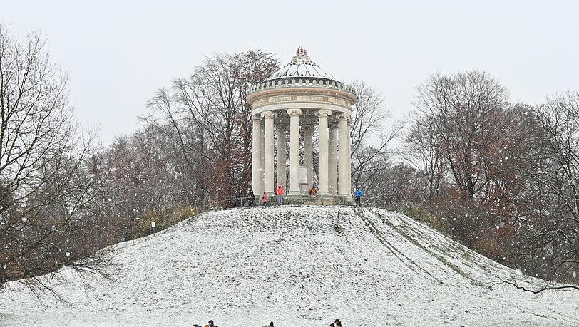 Spaziergänger laufen vor dem Monopteros durch den verschneiten Englischen Garten. Spaziergänger laufen vor dem Monopteros durch den verschneiten Englischen Garten.