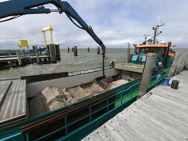 Ein Schiff mit Sand zur Erhöhung der Warften wird am Anleger der Hallig Hooge entladen.