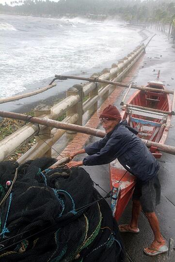 Ein Fischer versucht sein Holzboot zu sichern.