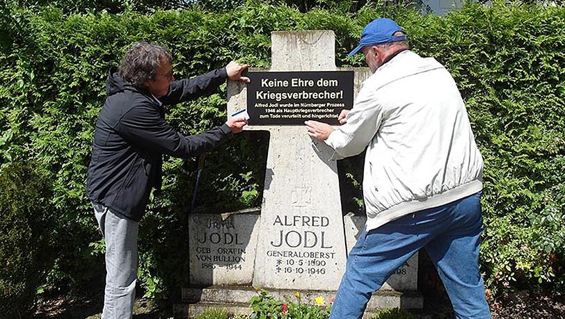 Der Aktionskünstler Wolfram Kastner (r.) und Rechtsanwalt Jürgen Arnold bringen ein Schild am Familiengrab der Jodls an. Der Aktionskünstler Wolfram Kastner (r.) und Rechtsanwalt Jürgen Arnold bringen ein Schild am Familiengrab der Jodls an.