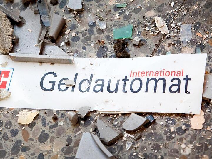 Splitter und ein abgerissenes Schild auf dem Fußboden vor einem gesprengten Geldautomaten.