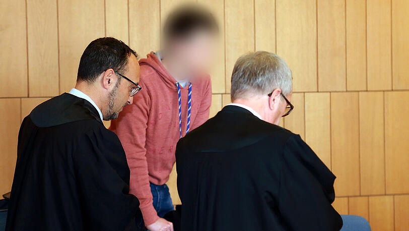Der Angeklagte steht mit Rechtsanwälten im Verhandlungssaal am Landgericht Traunstein.
