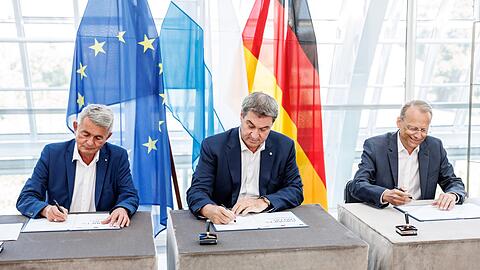 Ministerpräsident Markus Söder (CSU, M) unterzeichnet eine Vereinbarung für bevorstehende Veränderungsprozesse.