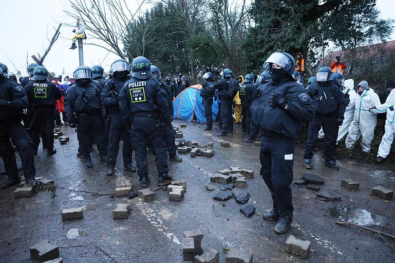 Aktivisten und Polizisten stehen sich am Rande des besetzten Braunkohleorts Lützerath direkt gegenüber.
