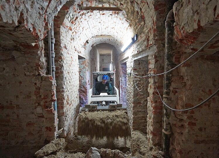 Ein Bagger schiebt Schutt durch den Keller.