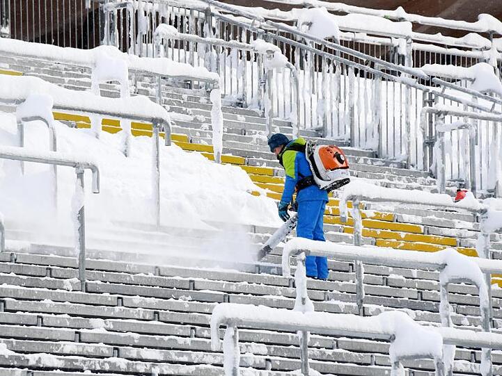 Ein Helfer befreit die Zuschauertribühne in der Chiemgau Arena in Ruhpolding (Bayern) vom Schnee. Foto: Tobias Hase/Archiv