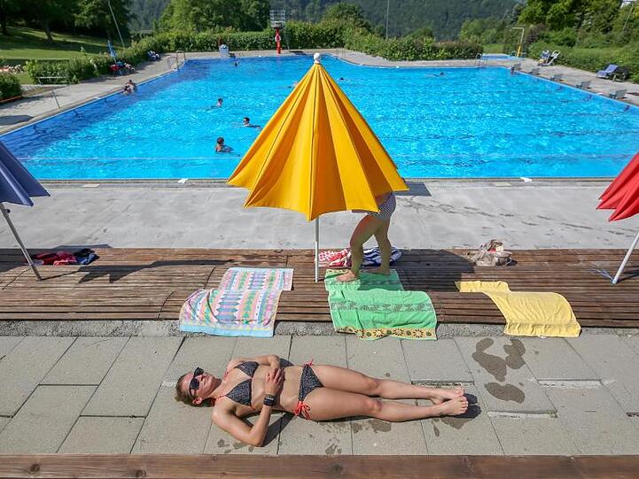 Ein Frau liegt im Freibad Zwiefalten auf einer Terrasse und sonnt sich.