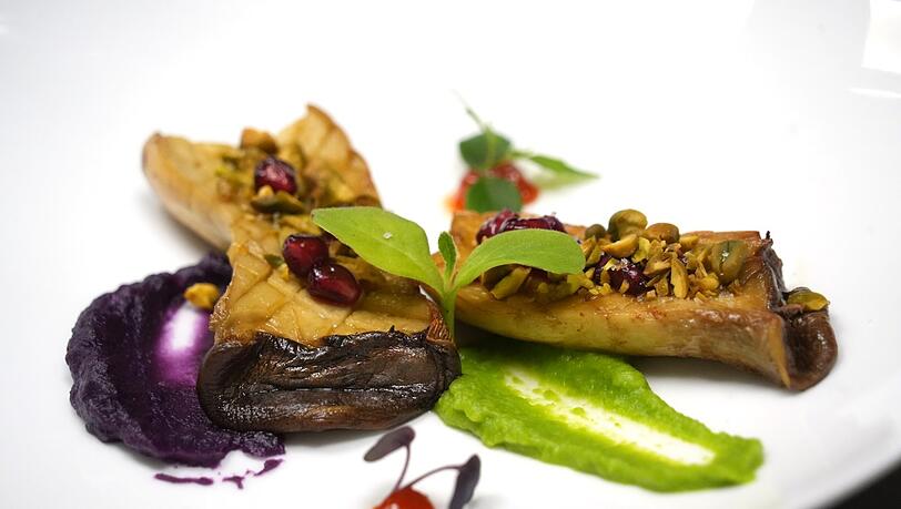 Dritter Gang: Sautéed King Oyster Mushroom – Kräuterseitlinge mit Erbsenpüree, lila Süßkartoffel, Granatapfel, Pistazie und Kochujang-Vinaigrette