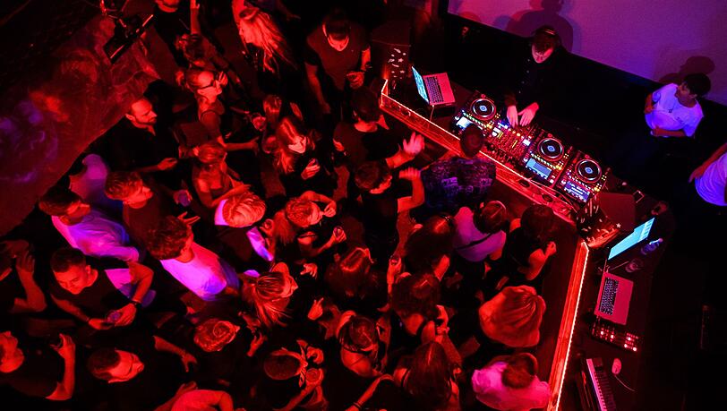 Menschen tanzen in einem Club zu elektronischer Musik.