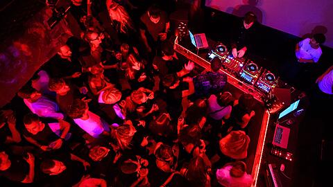 Menschen tanzen in einem Club zu elektronischer Musik.