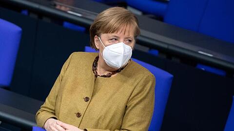 Bundeskanzlerin Angela Merkel (CDU) steht zu Beginn der Plenarsitzung im Deutschen Bundestag mit Schutzmaske an ihrem Platz.