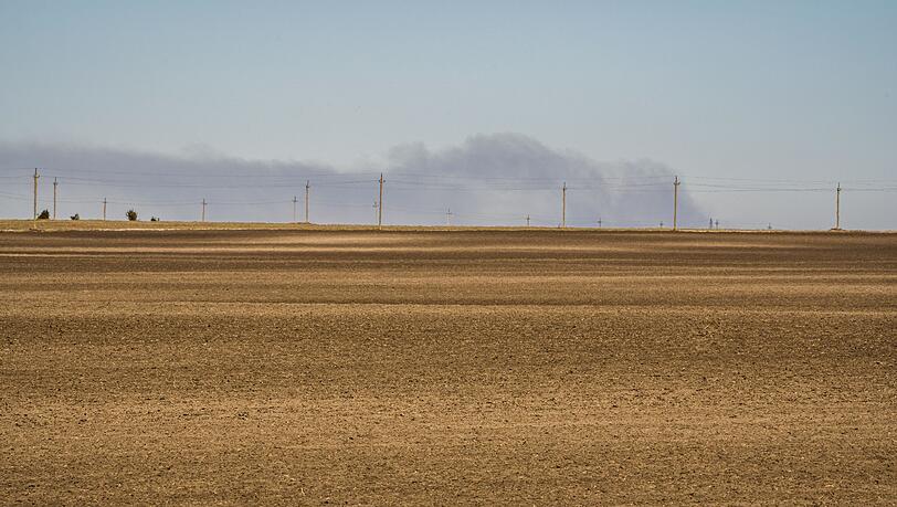 Am Horizont stehen Rauchschwaden über Feldern nach Bombeneinschlägen bei Volyn.