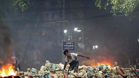 Ein Demonstrant stapelt Säcke auf einer Straße als Barrikade während eines Protestes in Yangon.