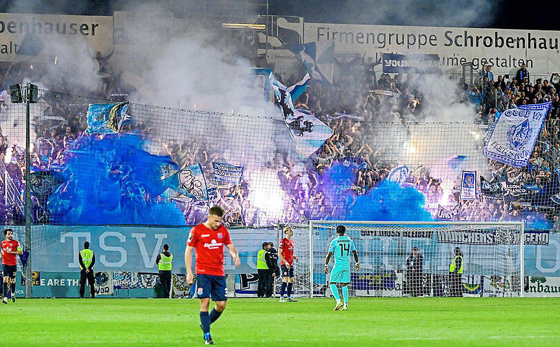 Zündelnde Löwen-Fans im Block, davor das ominöse Banner.  imago