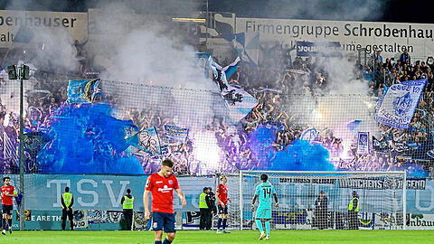 Zündelnde Löwen-Fans im Block, davor das ominöse Banner.  imago