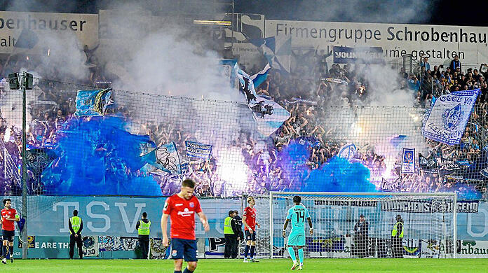 Zündelnde Löwen-Fans im Block, davor das ominöse Banner.  imago