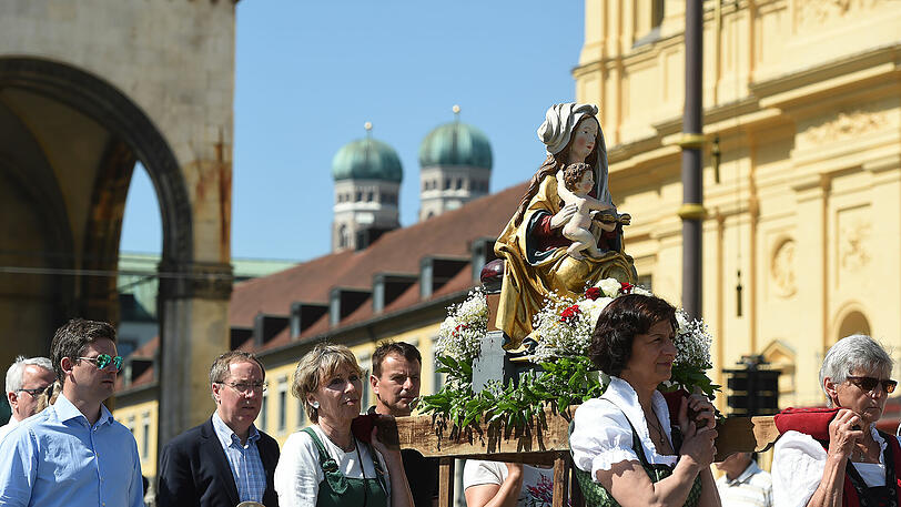 Die Marienstatue geschultert gehen Gläubige bei der Fronleichnamsprozession in München an der Feldherrnhalle vorbei.