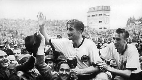 Der deutsche Stürmer und Kapitän Fritz Walter (M, oben) und sein Lauterer Teamgefährte Horst Eckel (r) werden nach dem Triumph im Fußball-WM-Finale im Berner Wankdorfstadion von begeisterten Anhängern vom Spielfeld getragen.