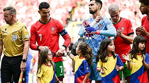 Fußball-EM 2024: Fußball-Superstar Cristiano Ronaldo wird von dem kleinen Einlaufmädchen am Arm berührt.