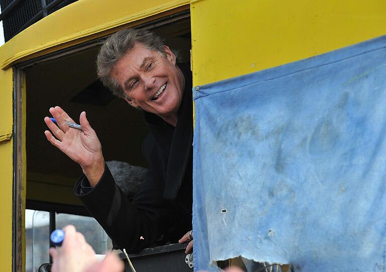 Der amerikanische Schauspieler und Sänger David Hasselhoff sitzt am 17.03.2013 in Berlin in einem Bus und fährt entlang der East Side Gallery, eines künstlerisch gestalteten Restabschnitts der früheren Berliner Mauer. Protestiert wird gegen die Bebauung des ehemaligen Todesstreifens und die damit verbundene Versetzung von Mauerelementen.