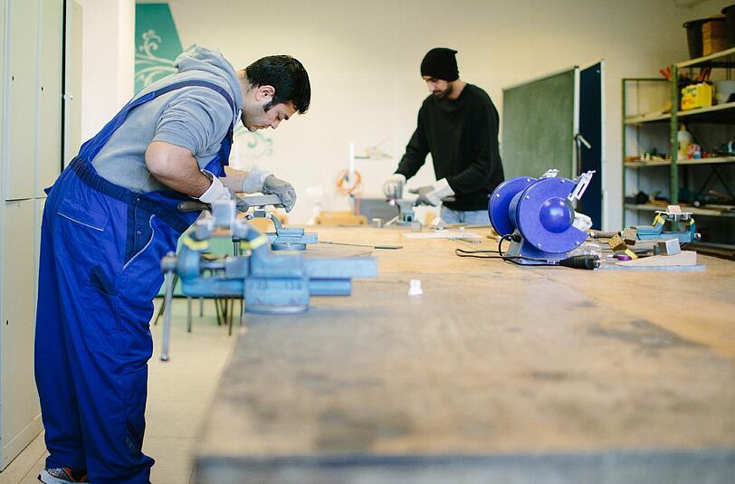 Der afghanische Flüchtling Sha Kah Ahmadi (l) und der indische Flüchtling Singh Satwinder feilen in der Fortbildungsakademie der Wirtschaft in Dresden an Metallwerkstücken. Handwerksbetriebe und die Bundesagentur für Arbeit haben mehr als 6000 Plätze für Flüchtlinge bereitgestellt. Foto: Oliver Killig/Archiv
