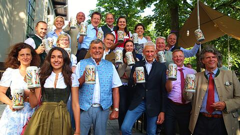 Wiesnwirte stehen zusammen mit ihren Familien und mit Maximilian Fliessbach (r), Künstler und Designer des Wiesn-Wirtkruges, bei einem Pressetermin und präsentieren den neuen Wiesn-Festkrug für das Oktoberfest 2019.