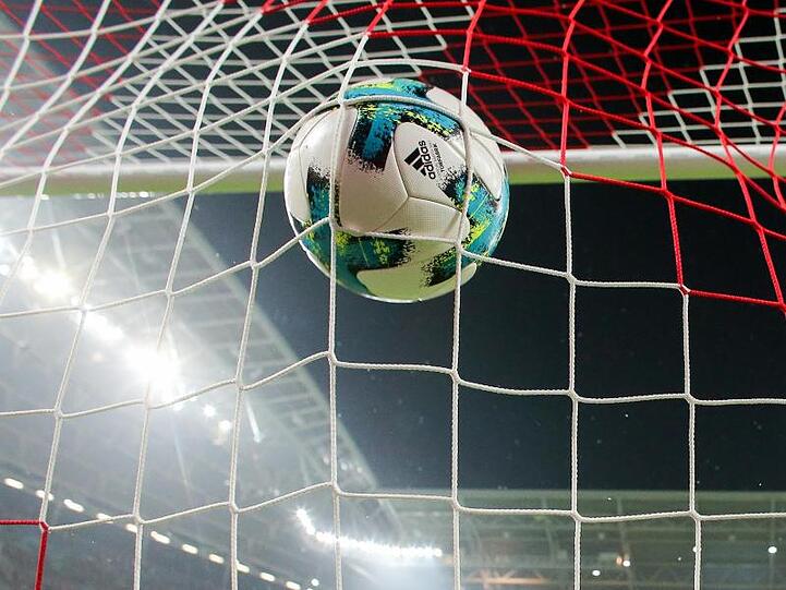 Ein Fußball fliegt ins Netz. Foto: Jan Woitas/zb/dpa/Symbolbild