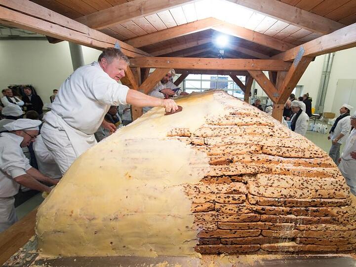Bäckermeister Thomas Schmidt bestreicht den Riesenstollen mit Butter und Zucker.