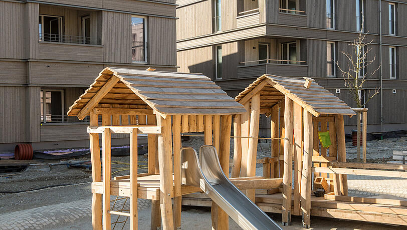 Ein Spielplatz mit einem der neuen Wohnh&auml;user im Hintergrund.