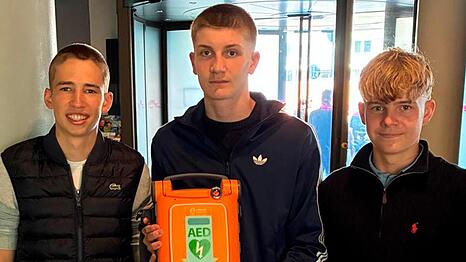 Drei junge Allg&auml;uer reanimieren in M&uuml;nchen einen Mann auf offener Stra&szlig;e und halten im Anschluss stolz ein lebensrettendes Hilfsmittel in die Kamera: den Automatisierten externen Defibrillator.