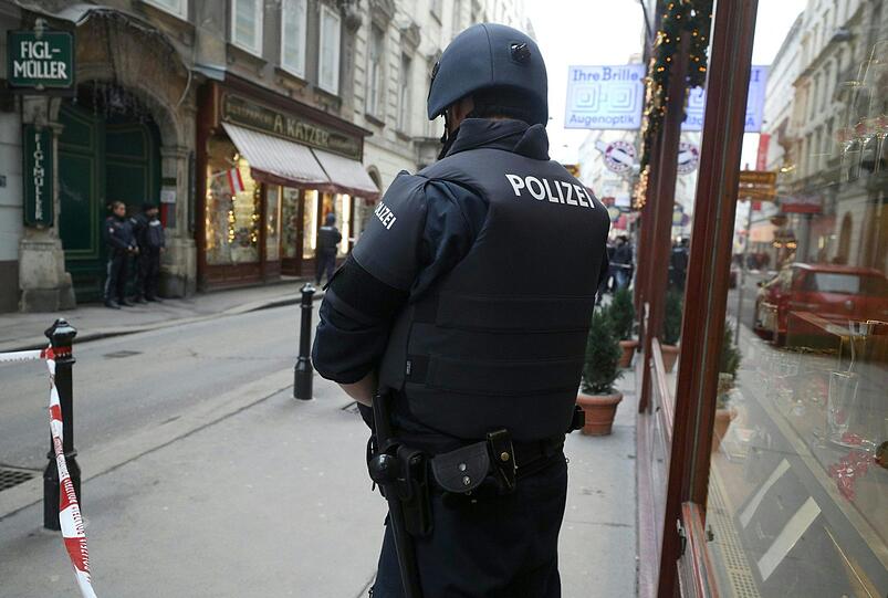 Ein Polizist steht am Tatort hinter einem Absperrband. Nach Schüssen in der Wiener City ist nach Angaben der Einsatzkräfte ein Menschen gestorben, ein weiteres Opfer wurde schwer verletzt.