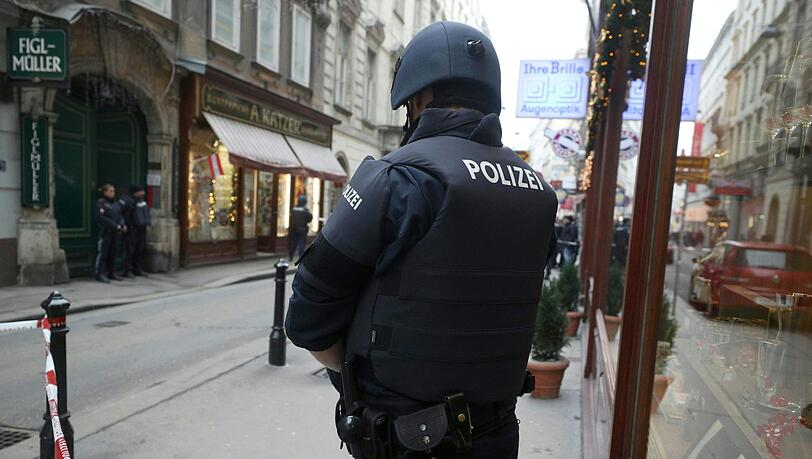 Ein Polizist steht am Tatort hinter einem Absperrband. Nach Schüssen in der Wiener City ist nach Angaben der Einsatzkräfte ein Menschen gestorben, ein weiteres Opfer wurde schwer verletzt. Ein Polizist steht am Tatort hinter einem Absperrband. Nach Schüssen in der Wiener City ist nach Angaben der Einsatzkräfte ein Menschen gestorben, ein weiteres Opfer wurde schwer verletzt.