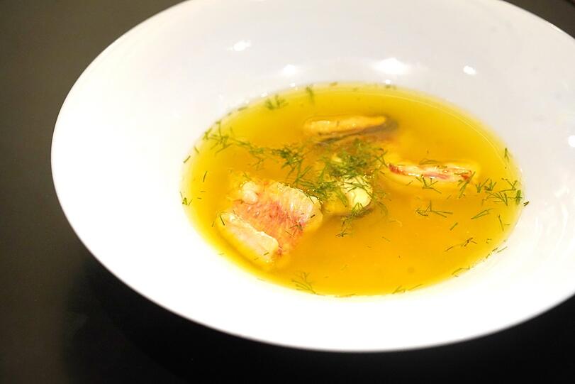 Zweiter Gang: Klare Bouillabaisse mit Barbe, Garnele, Muschel und Safran.