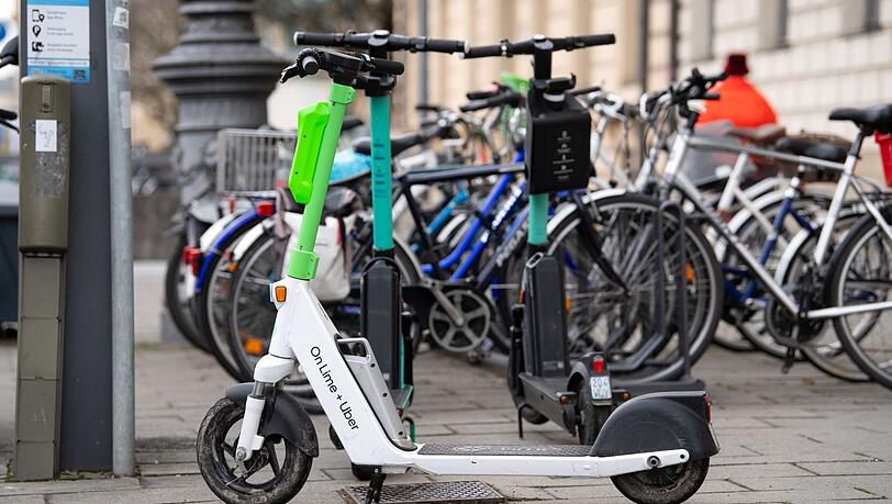 E-Scooter stehen in der Innenstadt auf einem Gehweg.