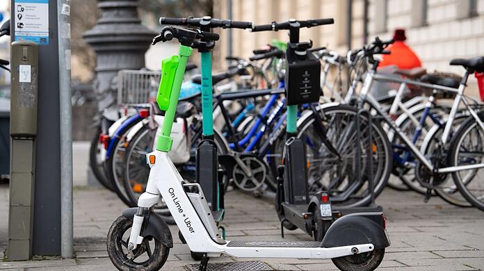 E-Scooter stehen in der Innenstadt auf einem Gehweg.