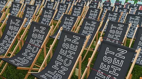 Liegestühle mit der Aufschrift Filmfest München stehen im Open Air Kino.
