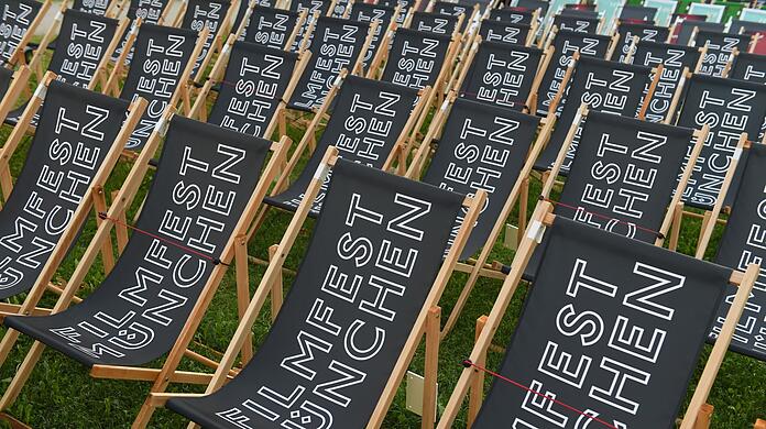Liegestühle mit der Aufschrift Filmfest München stehen im Open Air Kino.