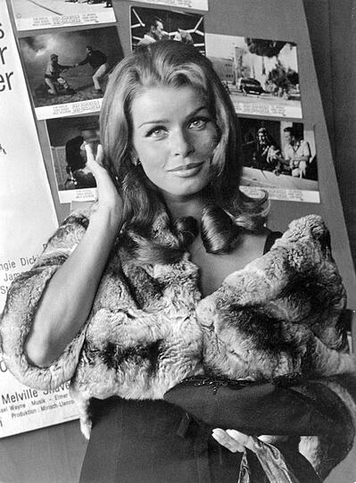 Archivfoto von 1966: Senta Berger posiert in Pelzjacke vor Fotos mit Szenen aus ihrem Film "Der Schatten des Giganten" in München.