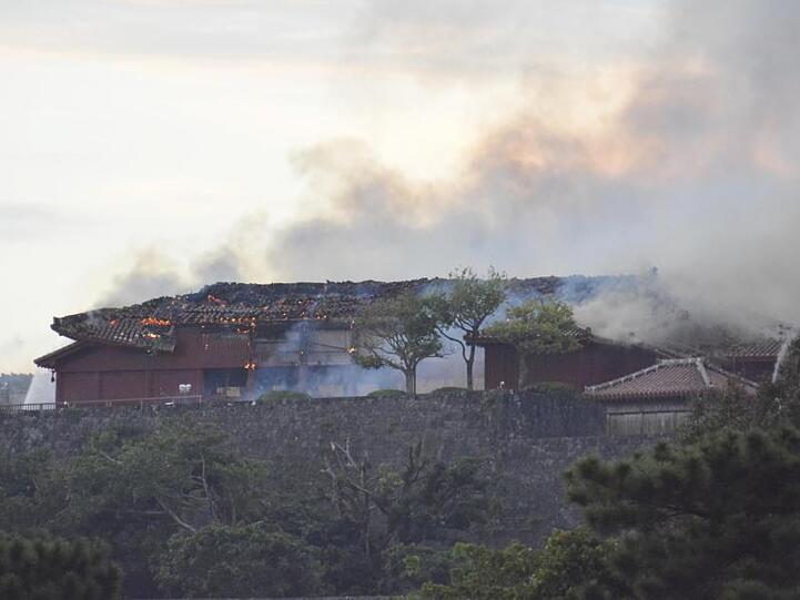 Das Hauptgebäude der Burg qualmt nach dem Brand.