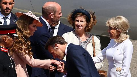 Mit einem Handkuss hat Emmanuel Macron Prinzessin Kate nach seiner Ankunft in Großbritannien begrüßt. Im Hintergrund schütteln sich Prinz William und Brigitte Macron die Hände.