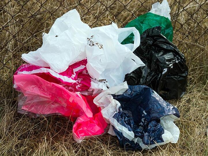 Weggeworfene Plastiktüten haben sich in einem Zaun verfangen.