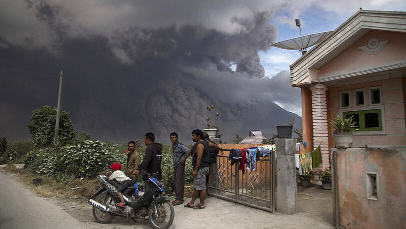Menschen versammeln sich in dem Ort Karo und schauen auf den Vulkan Sinabung.