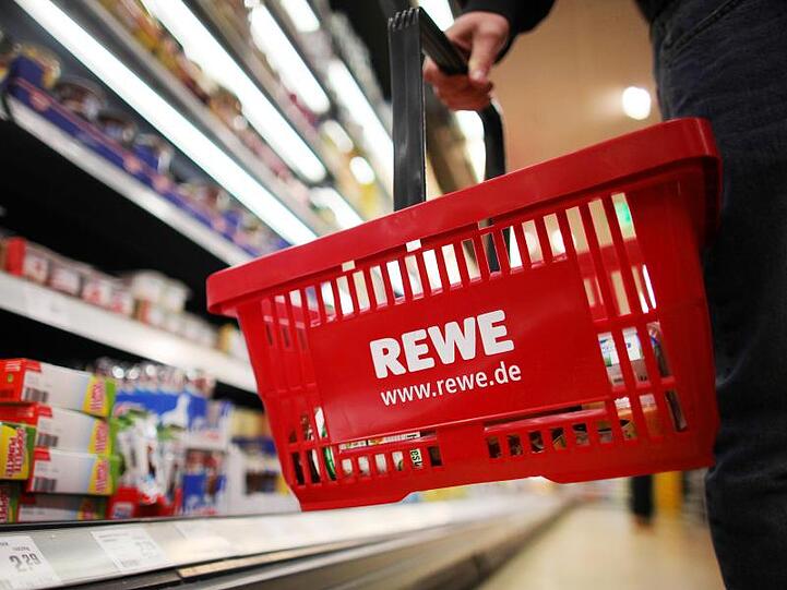 Ein Kunde geht in einem Rewe-Supermarkt mit einem Einkaufskorb am Kühlregal entlang. Foto: Oliver Berg/Archivbild