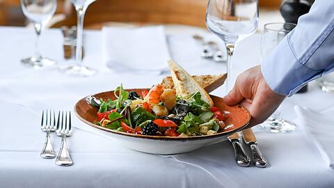 Ein Kellner serviert einen Salatteller in einem Restaurant.