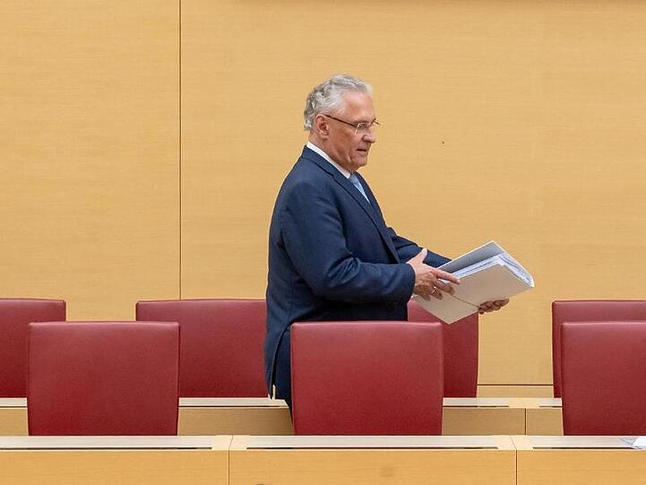 Joachim Herrmann (CSU), Innenminister von Bayern, geht während der Landtagssitzung an leeren Stühlen vorbei. Foto: Peter Kneffel/dpa