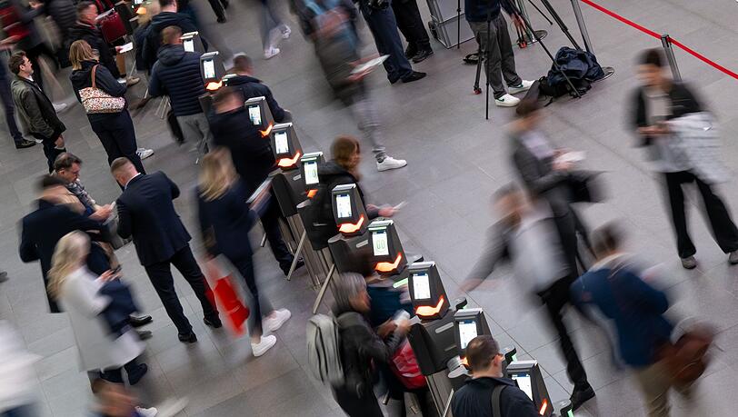 Besucher einer Messe gehen im Eingangsbereich durch die elektronische Einlasskontrolle.
