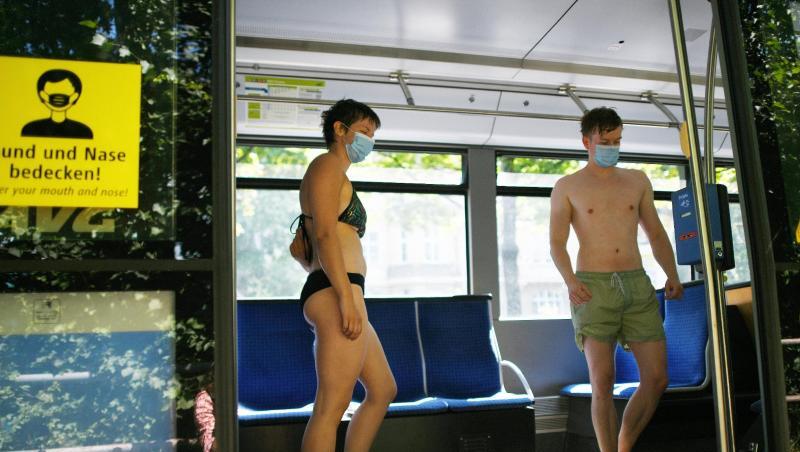 Eisbachschwimmer tragen Mund-Nasenschutz und stehen an der Tramhaltestelle Tivolistraße in der Tram. Foto: Angelika Warmuth/dpa Eisbachschwimmer tragen Mund-Nasenschutz und stehen an der Tramhaltestelle Tivolistraße in der Tram. Foto: Angelika Warmuth/dpa